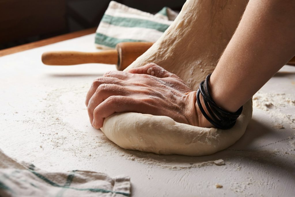 Baker kneading dough on a floured table