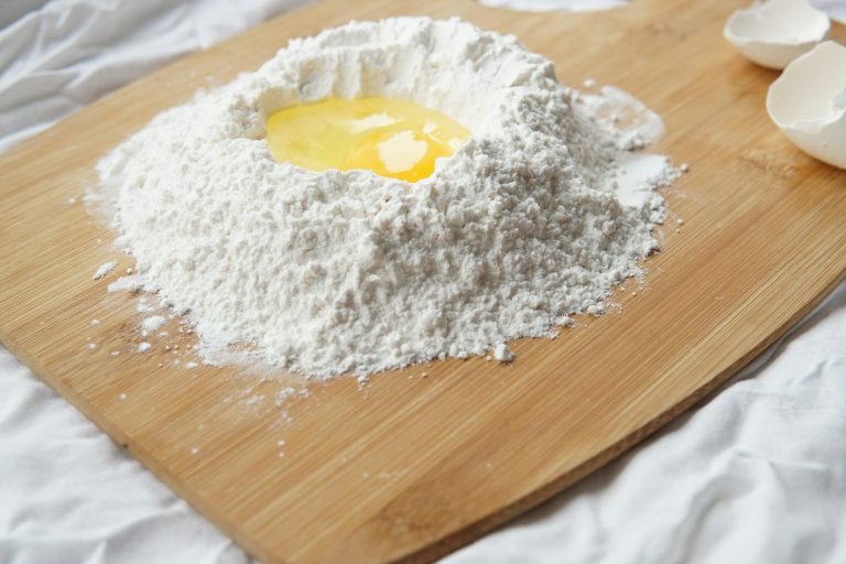 Mound of flour with an egg on a wooden board